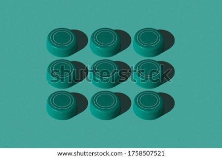 Nine square shaped plastic bottle caps on a blue background flat lay. Colourful pattern.