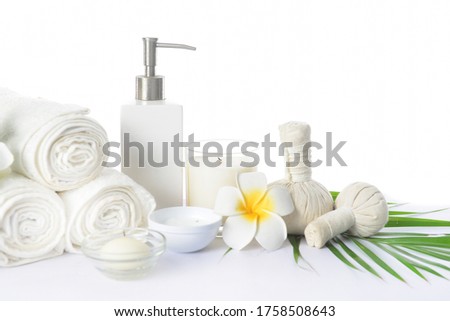 Spa setting with green frangipani leaves , orchid ,bottles of essential oil  , herbal ball, salt in bowl ,candle , herbal ,ball


