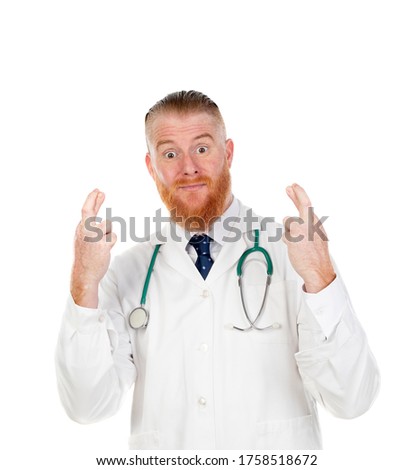 Redhead doctor crossing his finger for having luck isolated on a white background