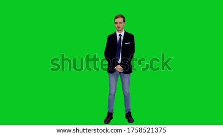 Young stylish businessman in suit jacket standing before presenting something on green screen background