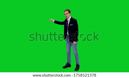 Young stylish businessman in suit jacket standing and presenting something on green screen background