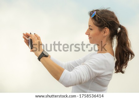 Girl taking selfie photo with phone on the cloud background