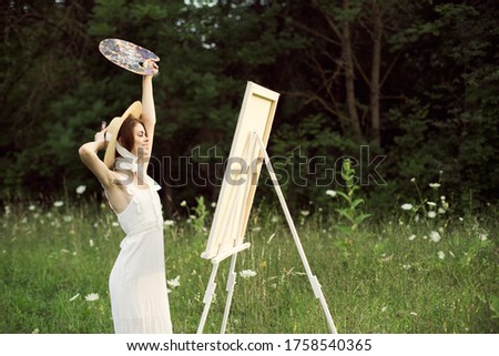 The artist paints a picture on nature in the forest and a palette canvas model