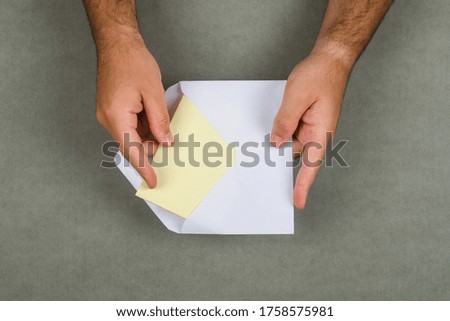 Business concept on grey background flat lay. man taking letter out of envelope.