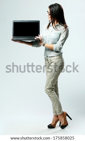 Young businesswoman looking on a laptop on gray background