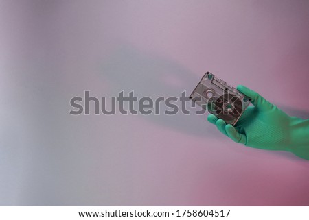 Green Hand holding audio cassette tape in the color light. Beautiful minimal in neon light. Minimalism retro style concept. Background pattern for design. 