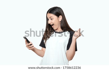 Cheerful happy young girl using mobile phone, smiling, posing on white background.