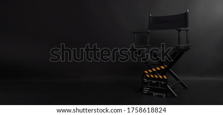 Director chair and Clapper board or movie slate use in video production or film and cinema industry. It's put on black blackground. Royalty-Free Stock Photo #1758618824