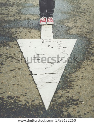 sneakers near the arrow marking of the road outdoor