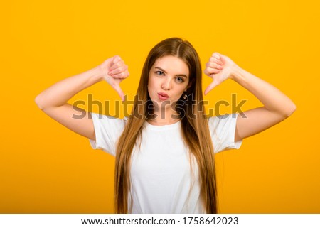 Isolated portrait of happy woman has toothy smile, closes eyes, feels pleasure from good compliment, stands over yellow wall. Positive emotions and feelings concept