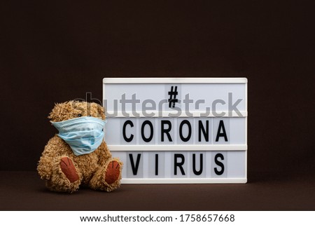 A teddy bear in a medical mask is sitting near a white sign that says "Coronavirus" on a dark background.
COVID-19 Coronavirus "STAY HOME SAVE LIVES" viral social media message sign with text 