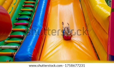 Image of joyful girl on a big inflatable trampoline at summer.