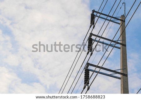 Cement high voltage poles and electric wire with fuse and white cloud with blue sky.
