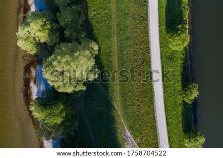 A pathway between the Isar river and channel in Flaucher, Munich, german nature aerial view