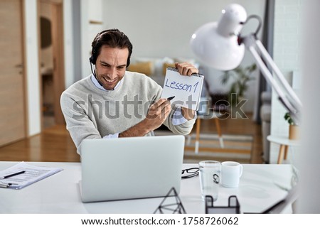Happy freelance worker holding online class while using computer at home. 