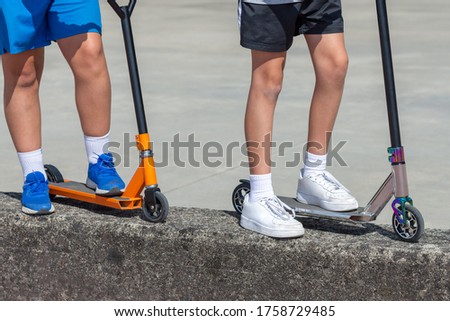 children's feet on multi-colored scooters, two children, close-up, outdoor entertainment