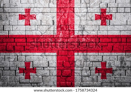 National flag of Georgia on brick  wall background.The concept of national pride and symbol of the country. Flag  banner on  stone texture background.