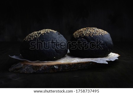 black burger rolls on a dark background with a close-up of the side horizontally