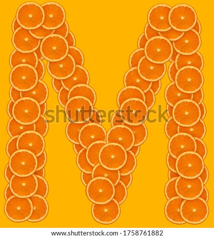 English letter "M" made from oranges on an orange background