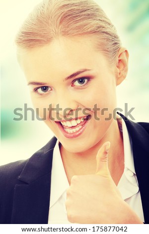 Young business woman showing OK sign, looking at camera and smiling. 