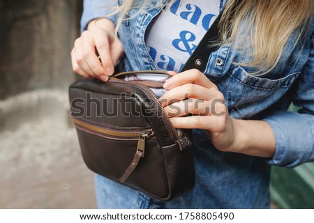Dark brown leather bag. The girl takes something out of the bag. Leather Cross Body Bags For Women. Close-up. Royalty-Free Stock Photo #1758805490