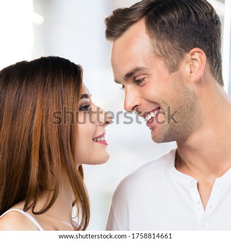 Profile side of smiling happy amazed couple at home. Face portrait image of standing close and looking at each other models in love concept. Man and woman posing together. Square composition.