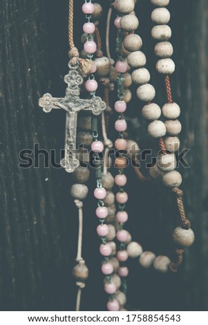 Close up old rosary against ancient wood doors background of church ruins. Vertical image.