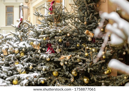close-up of the branches of a Christmas tree standing on the street under the snow.the tree is decorated with balloons, bows and garlands.happy New year and merry Christmas.