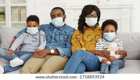 African American parents and cute small kids wearing protective masks at home. Stop the virus and epidemic diseases. Royalty-Free Stock Photo #1758893924