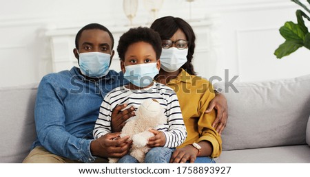 African american parents with cute small daughter wearing protective masks at home. Stop the virus and epidemic diseases.