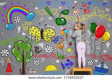 Little child drawing with colorful chalk on gray wall