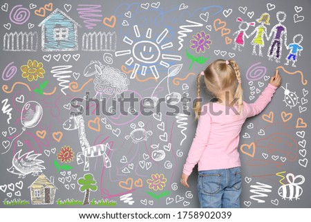 Little girl drawing with colorful chalk on gray wall