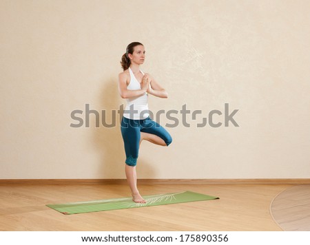 Caucasian woman is practicing yoga at studio (vrikshasana)