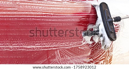 Red car washed in self serve carwash , detail on brush leaving strokes on side door, wide banner with empty space for text left side
