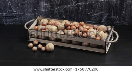 Walnuts and hazelnuts in a decorative wooden box on a dark background. Selection of healthy vegetarian food, healthy snack.