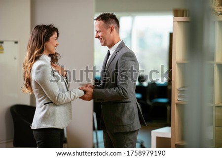 Businessman and businesswoman handshake in office. Young woman and man flirting in office.