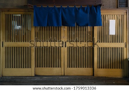 Abstract soft focus of traditional Japanese restaurants and shops style front view, curtain vivid blue fabric hangs in  front and on top of Japanese wooden slide door. 