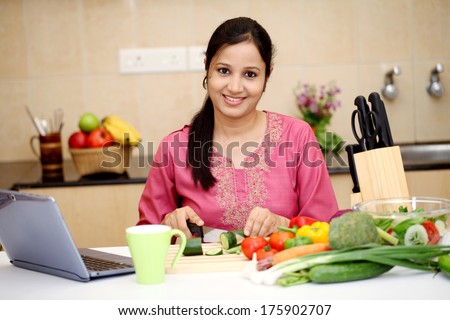Smiling young Indian woman cutting vegetables