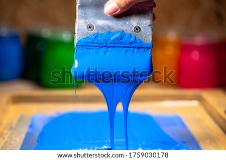 
blue color dripping from hand screen printing during printing tee shirt 
in tee shirt factory.