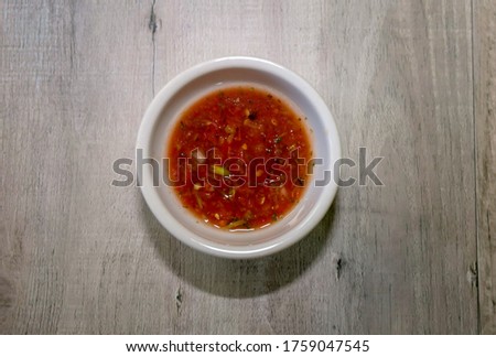 A small white bowl with red hot salsa for dipping.