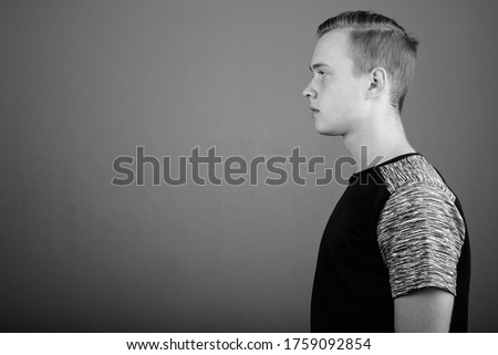 Young handsome man with blond hair against gray background