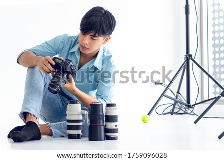 Young photographer is taking pictures in the studio with a digital camera