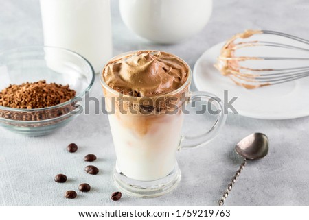 Iced Dalgona Coffee, fashionable fluffy creamy whipped coffee on a light coloured background.