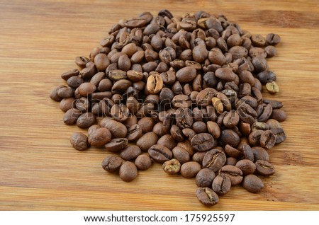 Heap of coffee beans on bamboo wooden surface