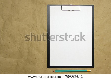 A tablet with a white sheet of A4 format with pencil on a beige craft paper. Concept of new opportunities, ideas, undertakings, innovations. Stock photo with empty place for your text and design.
