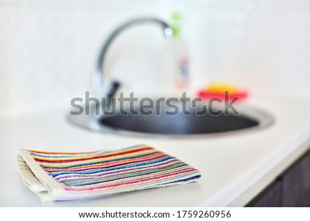 Kitchen towel and sink without dirty dishes background. Dishcloth on kitchen countertop. Cleaning and dish washing concept.