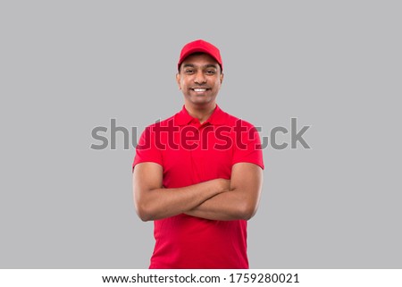Delivery Man Standing Hands Crossed Smiling. Indian Delivery Boy in Red Uniform Isolated Royalty-Free Stock Photo #1759280021