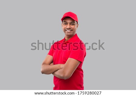 Delivery Man Standing Hands Crossed Smiling. Indian Delivery Boy in Red Uniform Isolated Royalty-Free Stock Photo #1759280027