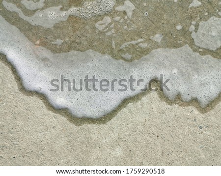 Water stains and white bubbles on the concrete floor.