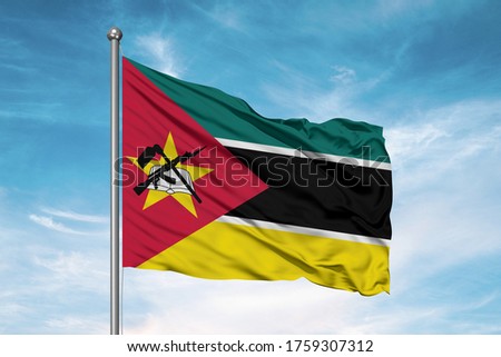 Mozambique national flag cloth fabric waving on beautiful sky.